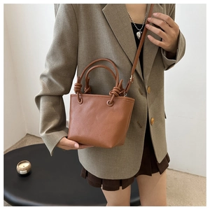 Detail of brown lychee texture leather bucket bag with knotted handle and shoulder strap