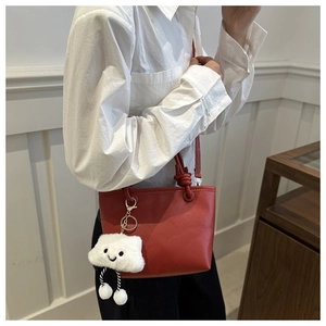 Detail of red textured leather bucket bag with a cute white cloud plush pendant charm