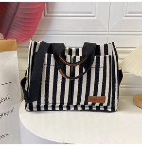 Detail view of striped canvas tote bag with leather handles and fashion logo label
