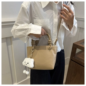 Close-up of khaki leather tote bag with knot handle and plush cloud charm detail