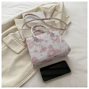 Detail of printed butterfly pattern on white leather crossbody bag with golden hardware