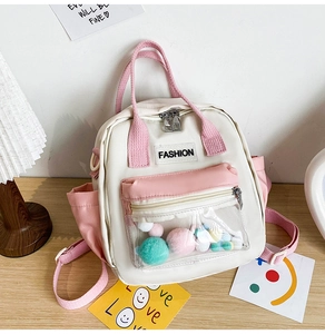 Dettaglio zaino in nylon con tasca frontale in PVC trasparente e pompon colorati