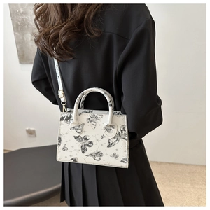 Back view of a model wearing a white butterfly print square shoulder bag with gold hardware