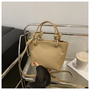 Detail of khaki lychee grain leather bucket bag with chunky rope knot handle and gold hardware