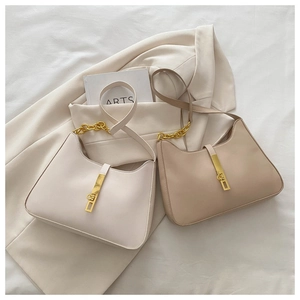 Detail of minimalist leather underarm bags with golden chain and sleek buckle closure
