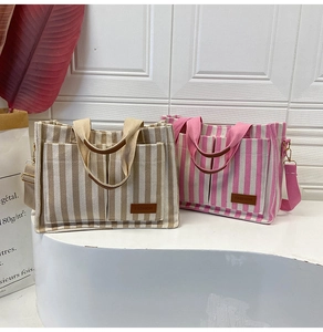 Detail of striped canvas tote bags in khaki and pink with front pockets and straps