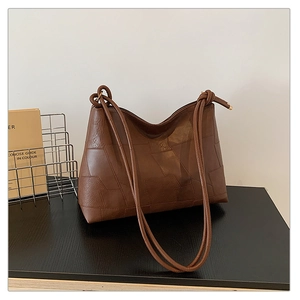 Detail of brown faux leather shoulder bag with geometric patchwork and knotted strap design