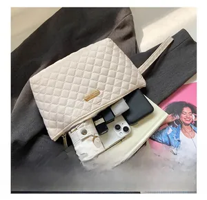 Detail view of cream quilted clutch showing large capacity for umbrella, phone and makeup