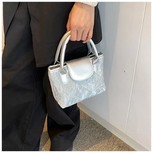 Close-up of silver quilted crossbody bag with textured metallic finish and round handle