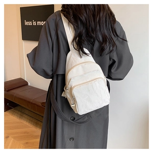 Détail du sac bandoulière crème en nylon avec plusieurs poches zippées et texture plissée