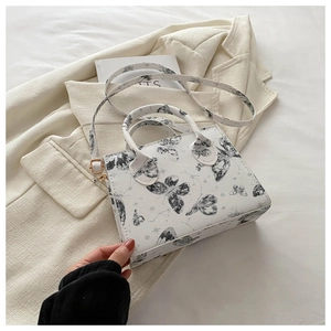 Detail of artistic butterfly and star print on white leather shoulder bag with gold hardware