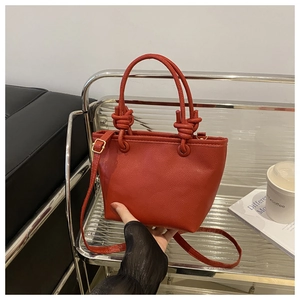 Detail of red lychee grain leather bucket bag featuring unique knotted handle design
