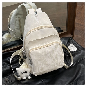 Détail du sac bandoulière blanc à motif marbre avec breloque peluche sur veste en cuir