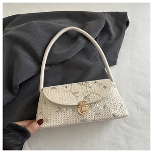 Detail of cream straw bag with floral lace embroidery and gold twist lock closure