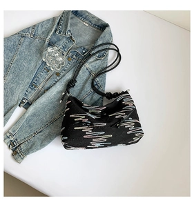 Detail shot of black tote bag with colorful embroidery and rope strap on white background