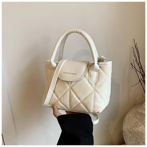 Detail view of cream quilted crossbody bag with FASHION & BAGS text and top handle