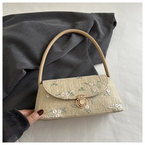 Close-up of woven straw handbag featuring elegant floral embroidery and vintage metal clasp