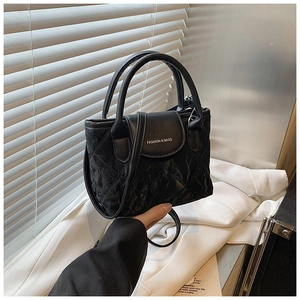 Detail of a black pleated crossbody bag featuring a metal chain strap and logo