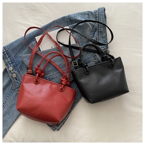 Close-up of litchi grain leather texture and knot detail on red and black bucket bags