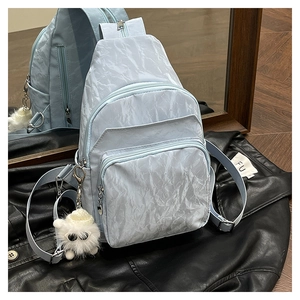 Détail du sac bandoulière bleu clair avec texture plissée et pendentif en peluche