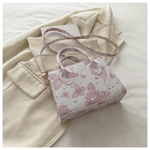 Close-up of butterfly print and golden hardware on the textured white shoulder bag