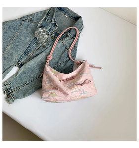 Detail of pink shoulder bag with bow, embroidery, and textured leather finish