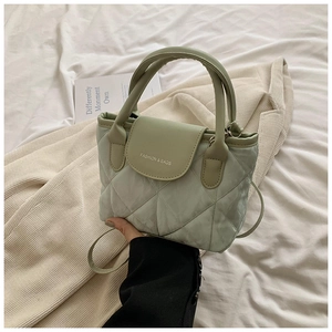 Close-up of a light green quilted crossbody bag with FASHION & BAGS lettering detail