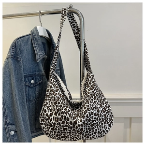 Détail du sac cabas en toile à motif léopard suspendu à côté d'une veste en jean