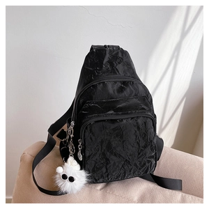 Détail du sac de poitrine en nylon noir plissé avec zips et un porte-clé monstre en peluche