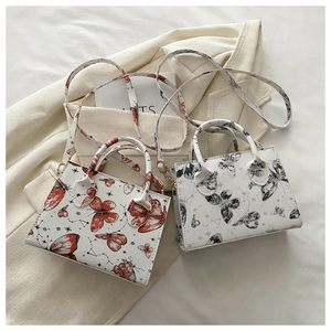 Detail of printed butterfly mini crossbody bags on white fabric with star patterns