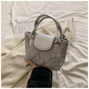 Detail of silver quilted handbag with beige flap and adjustable shoulder strap