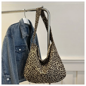 Détail d'un sac hobo léopard en toile épaisse suspendu à côté d'une veste en jean bleue