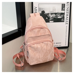 Gros plan du sac bandoulière rose en nylon avec texture plissée et fermetures argentées