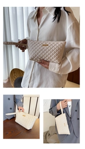 Macro detail of quilted beige envelope bag with golden metal logo and zipper texture