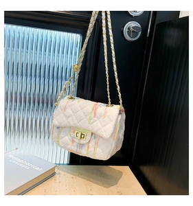 Detail of white quilted crossbody bag with colorful patterns and golden metal turn-lock closure