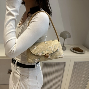 Straw shoulder bag with floral lace embroidery and vintage buckle on female model