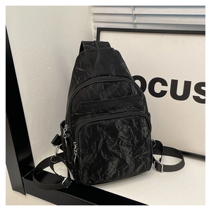 Gros plan d'un sac bandoulière noir avec tissu texturé et plusieurs poches zippées