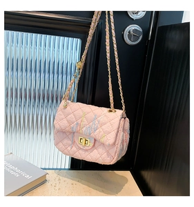 Detail of pink quilted crossbody bag with colorful embroidery and gold chain strap