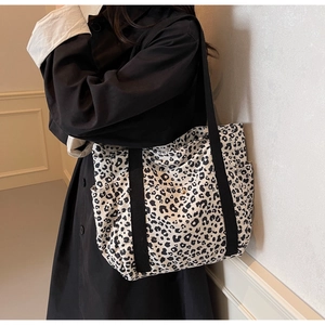 Detail of leopard print canvas tote bag with side pocket and black shoulder strap