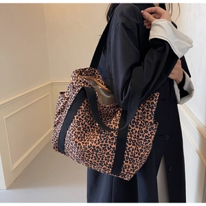 Detailed view of leopard print tote bag featuring black wide straps and a side pocket