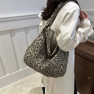 Grand sac hobo en toile à imprimé léopard porté par un mannequin dans un intérieur