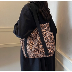 Detailed side pocket and nylon webbing on a leopard print canvas tote bag