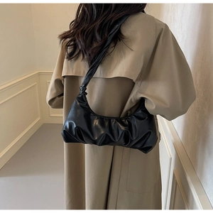 Détail d'un sac demi-lune plissé noir avec texture en similicuir lisse et bandoulière