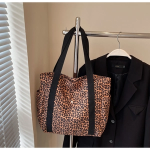 Detail of leopard print tote bag featuring side pockets and wide black shoulder straps