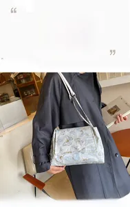 Detail of white shoulder bag with intricate blue butterfly embroidery and chain strap