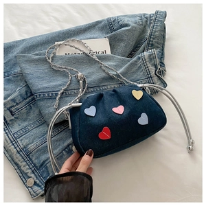 Détail du sac bandoulière en denim bleu avec patchs cœurs colorés et chaîne en argent