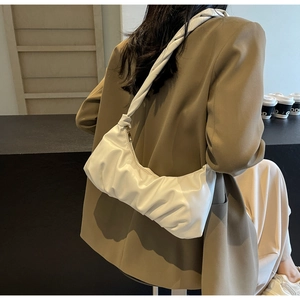 Détail du sac à bandoulière blanc plissé avec un design élégant porté par un mannequin