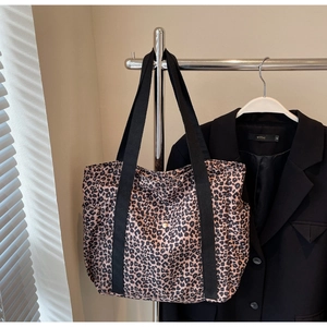 Detail of leopard print tote bag with black nylon straps and side pocket on a hanger