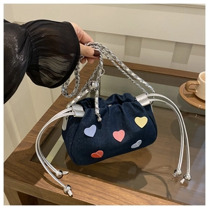 Détail d'un sac seau en jean bleu avec écussons cœurs colorés et bandoulière chaîne