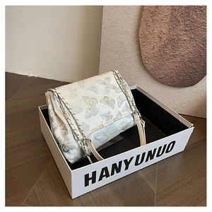 Detailed embroidery of butterflies on a cream chain shoulder bag in a display box